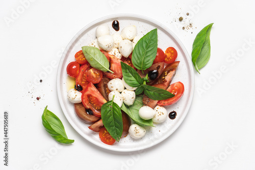 Caprese salad with tomatoes, basil, mozzarella, balsamic sauce and olive oil. Traditional Italian food. Top view, white background, copy space photo