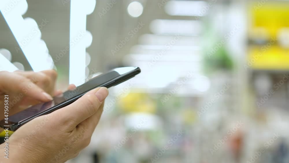 Woman Looks at Goods in Online Store . Buy Directly on Smartphone. Woman at in supermarket Using Smartphone Buys in Internet Shop. Woman Looks at Goods in Online Store . Buy Directly on Smartphone. Woman at in supermarket Using Smartphone Buys in Internet Shop.