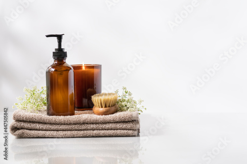 Beauty spa treatment and relax concept. Towel, glass dispenser and body massage brush. White background, copy space
