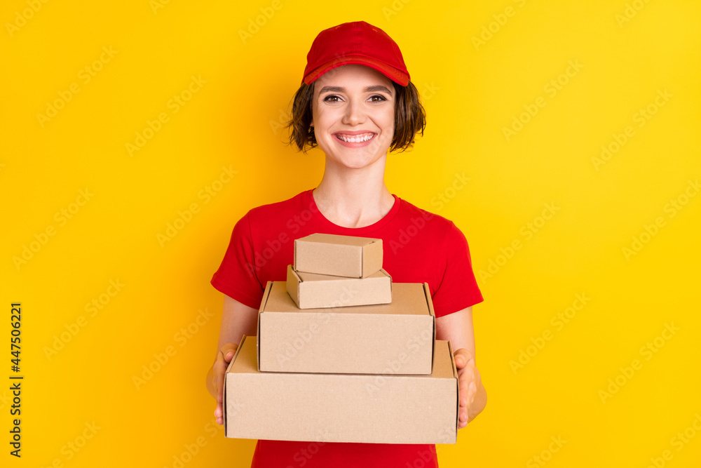 Photo of nice optimistic brown hair lady hold box wear t-shirt cap isolated on yellow background Photo of nice optimistic brown hair lady hold box wear t-shirt cap isolated on yellow background