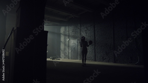 Woman with fit ball walking in gym. Sportswoman standing at wall with ball