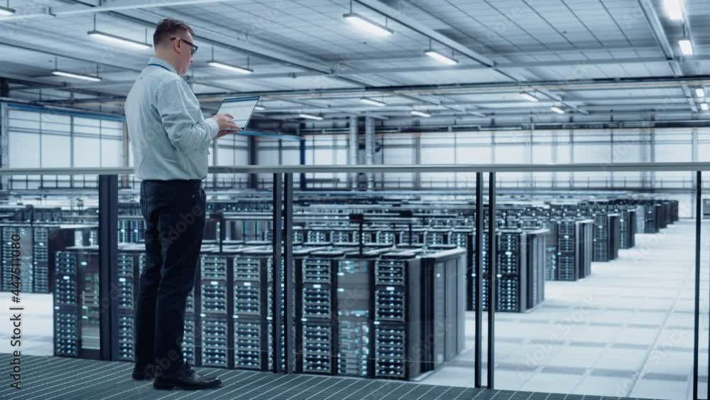 Data Center Engineer Using Laptop Computer. Server Farm Cloud Computing Specialist Facility with Adult Male System Administrator Working with Data Protection Network for Cyber Security. Data Center Engineer Using Laptop Computer. Server Farm Cloud Computing Specialist Facility with Adult Male System Administrator Working with Data Protection Network for Cyber Security.