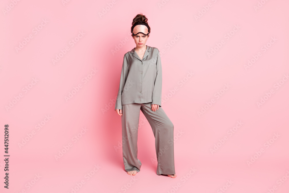 Full length body size view of attractive moody sullen girl wearing pajama bad mood isolated over pink pastel color background Full length body size view of attractive moody sullen girl wearing pajama bad mood isolated over pink pastel color background