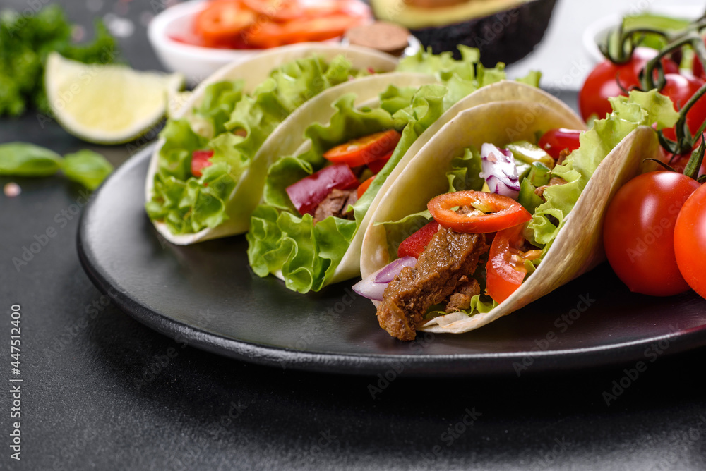 Mexican tacos with beef, tomatoes, avocado, onion and salsa sauce