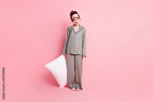 Full length body size photo of girl in pajama keeping pillow unhappy sad cannot sleep insomnia isolated on pastel pink color background