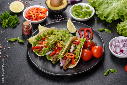 Mexican tacos with beef, tomatoes, avocado, onion and salsa sauce