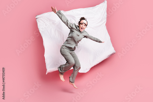 Full length body size view of pretty crazy cheerful girl jumping on bed having fun isolated over pink pastel color background