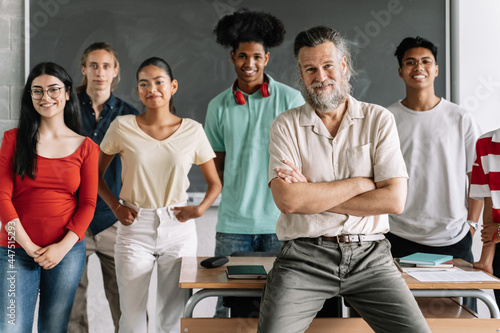 Multi-racial group of teenager secondary school students and friendly senior teacher with beard in the classroom of the High School. Cultural Diversity in Education photo