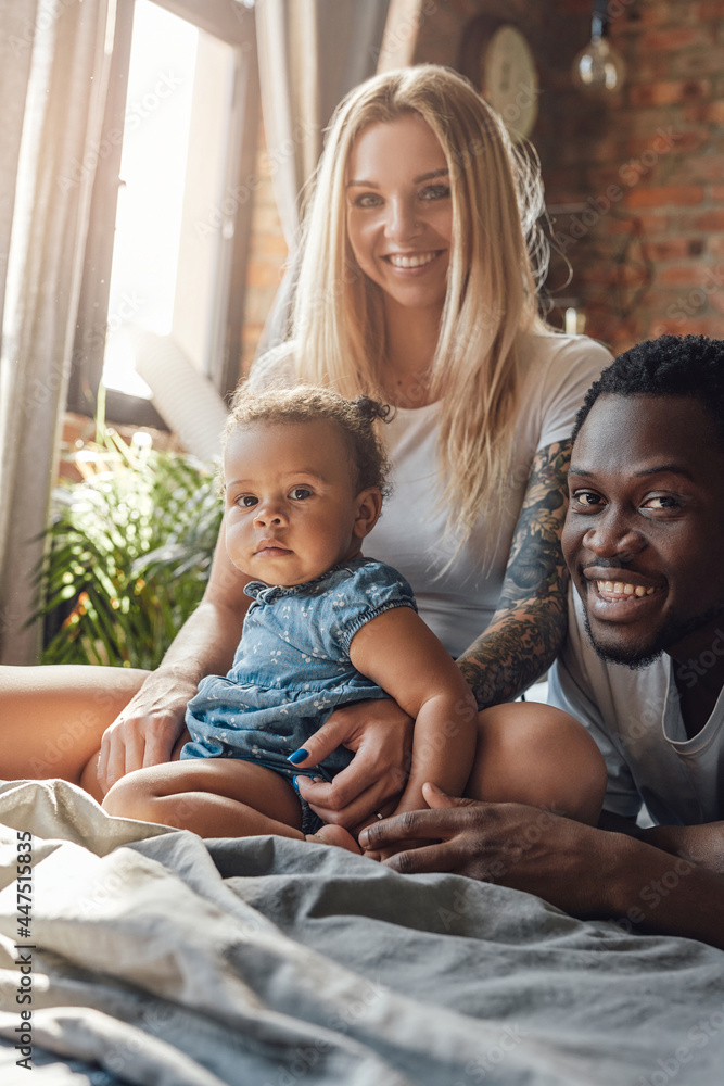 Obraz premium Joyful mixed race couple and their daughter in bedroom