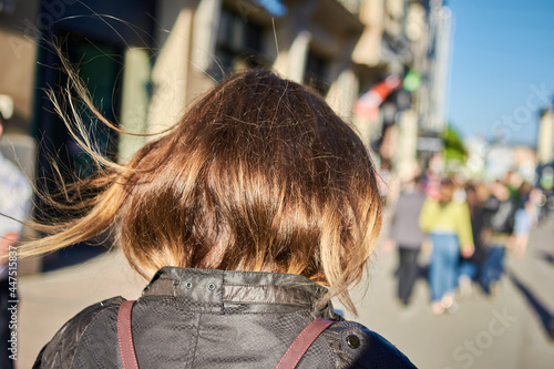 Rear view of the woman with brown hair and walking on the city street © mediaeugene