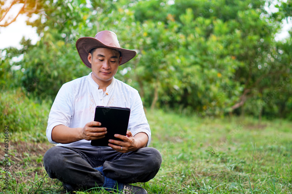 Concept : using smart device everywhere in daily life. Handsome Asian gardener sit in garden and hold smart tablet to study online and search knowledge about agriculture. Concept : using smart device everywhere in daily life. Handsome Asian gardener sit in garden and hold smart tablet to study online and search knowledge about agriculture.