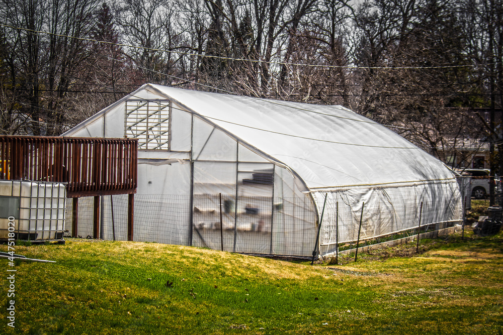 Big greenhouse down the hlll in residential back yard in winter. Big greenhouse down the hlll in residential back yard in winter.