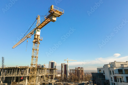 Aerial view of high tower crane and residential apartment buildings under construction. Real estate development.