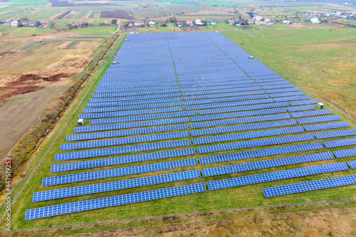 Aerial view of solar power plant on green field. Electric farm with panels for producing clean ecologic energy.