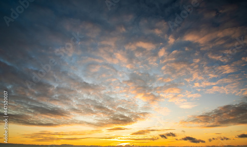 Canvas Print Dramatic sunset landscape with puffy clouds lit by orange setting sun and blue sky
