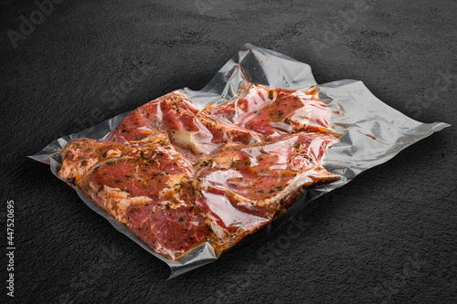 Vacuum-packed meat, on dark stone background, pork steak. Semifinished.