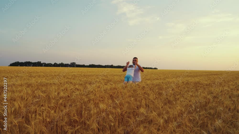 Slow motion father holding little son by hands and spinning in wheat field at sunset. Arc shot happy parent and child enjoying time together. Concept of family Slow motion father holding little son by hands and spinning in wheat field at sunset. Arc shot happy parent and child enjoying time together. Concept of family