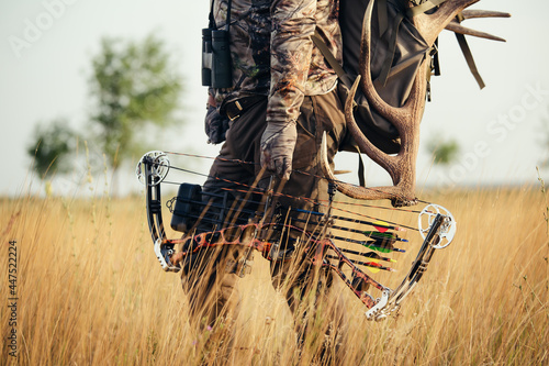 Принти на полотні Close up shot of a hunter dressed in camouflage clothing holding a modern bow