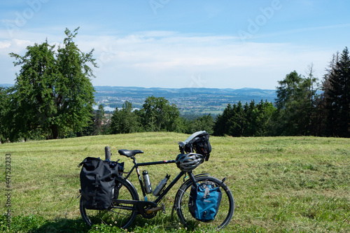 A heavily packed touring bicycle parked on a meadow with beautiful view