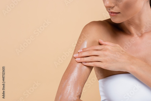 Behang cropped view of young woman applying sunblock isolated on beige
