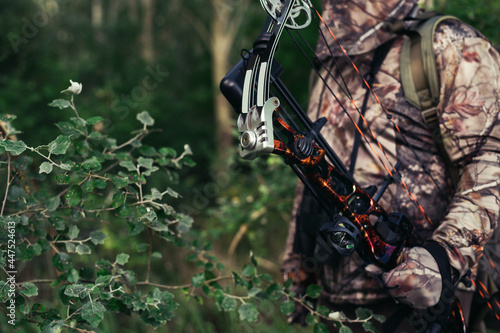 Hunter in the woods with bow and arrow ready to take aim at his prey