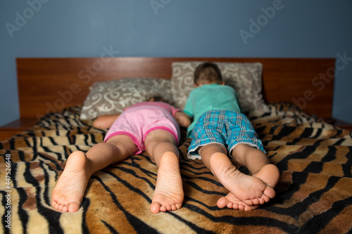 Brother and sister relaxing. Feet of chldren on a bed. photo