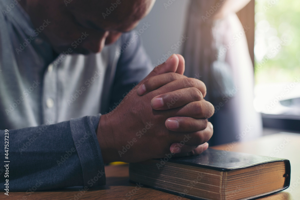Obraz premium Prayer and bible concept. Asian senior man praying, hope for peace the world and free from coronavirus, Hand in hand together, believes and faith in christian religion at home.