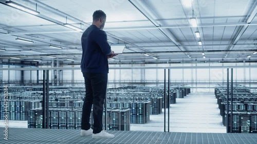 Wallpaper Mural Data Center Engineer Using Laptop Computer. Server Farm Cloud Computing Specialist Facility with African American Male System Administrator Working with Data Protection Network for Cyber Security. Torontodigital.ca