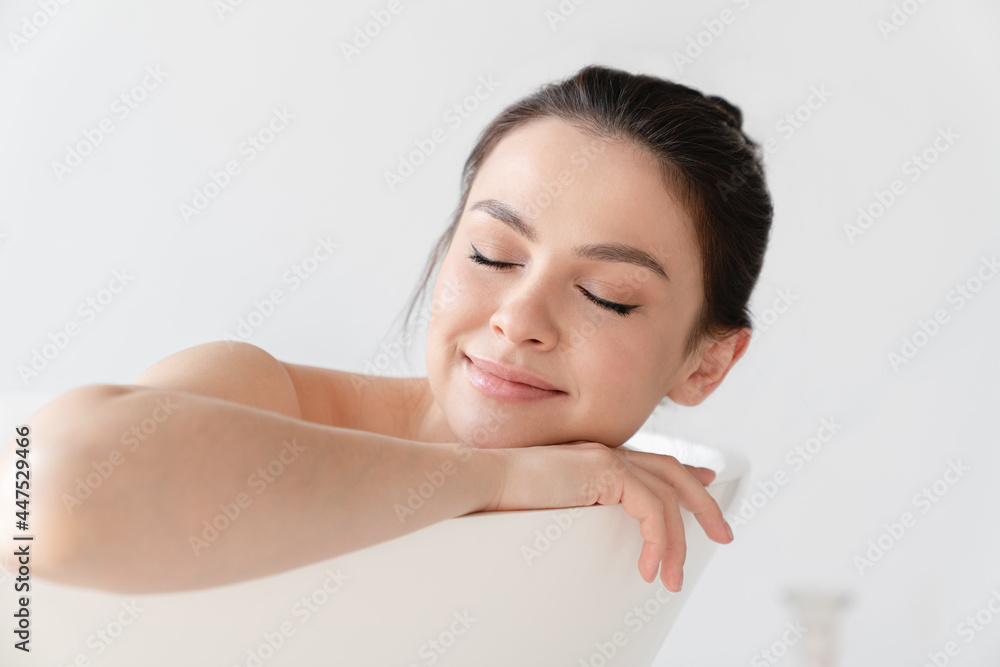 Serene peaceful sleeping young woman relaxing in hot warm bath shower taking care of her body and skin at home. Spa treatment, stress relief concept Serene peaceful sleeping young woman relaxing in hot warm bath shower taking care of her body and skin at home. Spa treatment, stress relief concept