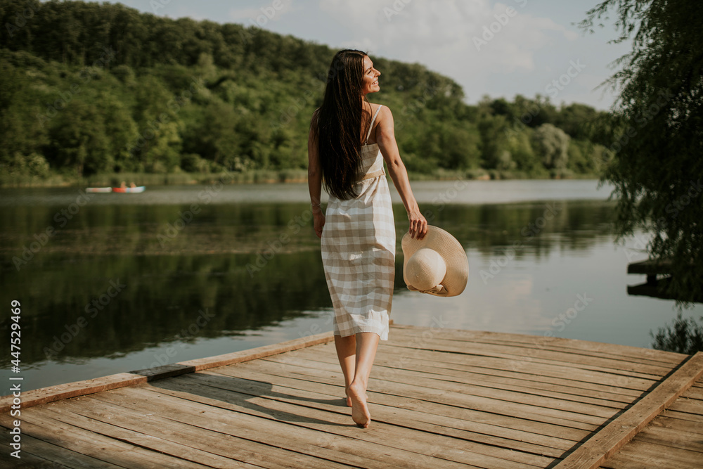Relaxing young woman standing on wooden pier at the lake Relaxing young woman standing on wooden pier at the lake