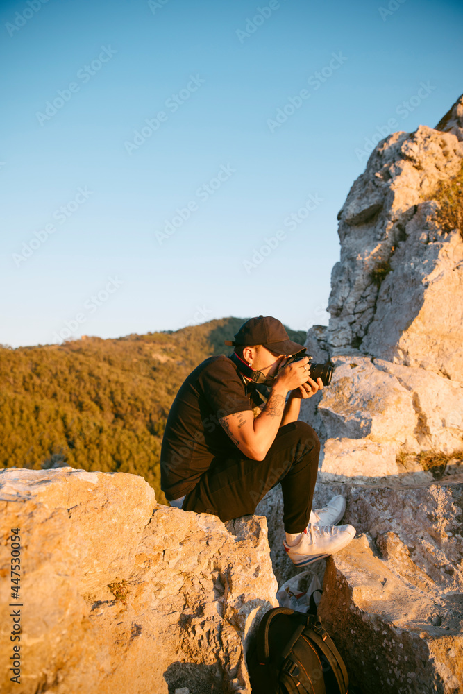 Hombre joven haciendo fotos en los alto de una montaña al atardecer Hombre joven haciendo fotos en los alto de una montaña al atardecer