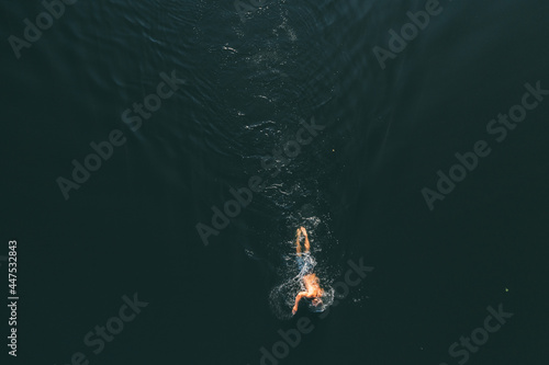 Man with a beautiful body swims in the lake. Summer mood