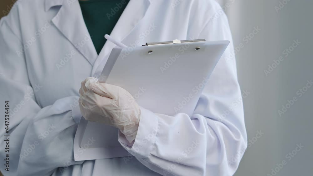 Close-up unrecognizable woman doctor nurse unknown practitioner in uniform white coat wears latex gloves holds folder with documents papers hands writes diagnosis medical prescription notes with pen Close-up unrecognizable woman doctor nurse unknown practitioner in uniform white coat wears latex gloves holds folder with documents papers hands writes diagnosis medical prescription notes with pen
