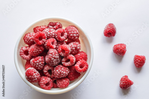 Frozen raspberries in a bowl. Fresh red raspberries isolation on white