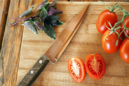 Basil, tomatoes on a branch, a cut tomato and a knife
