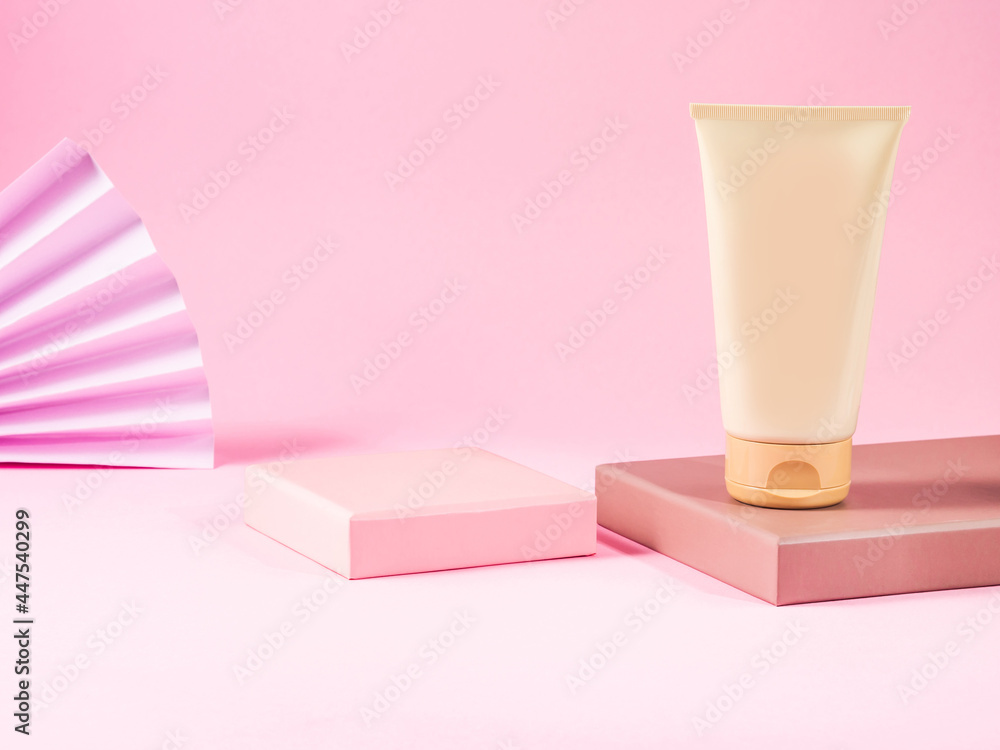 Geometric podium displays body care generic cream tube on pink background. Geometric podium displays body care generic cream tube on pink background.