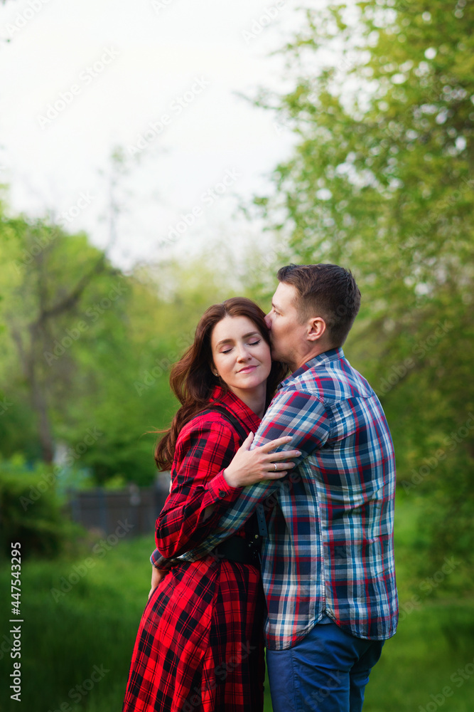 Loving couple hugging while walking relaxing in summer park together. Girlfriend and boyfriend having fun outdoors, kissing and hugging, love concept. Loving couple hugging while walking relaxing in summer park together. Girlfriend and boyfriend having fun outdoors, kissing and hugging, love concept.