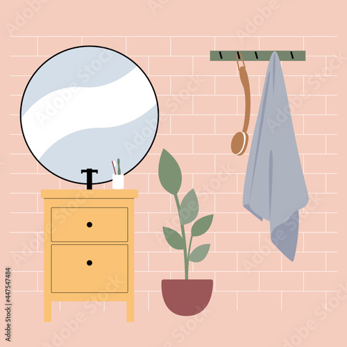 Nice bathroom interior with pink tiles, yellow vanity unit, sink and round mirror. Blue towel in the bathroom on a hanger.