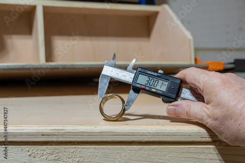 Man holding a digital Vernier Calliper measurung the external diamater of a brass fitting photo