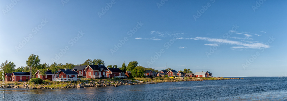 idyllic Baltic Sea panorama landscape with red cottages on the shoreline under a blue sky