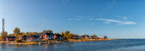 idyllic Baltic Sea panorama landscape with red cottages on the shoreline under a blue sky in autumn photo