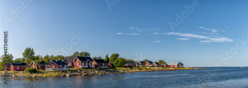 idyllic Baltic Sea panorama landscape with red cottages on the shoreline under a blue sky