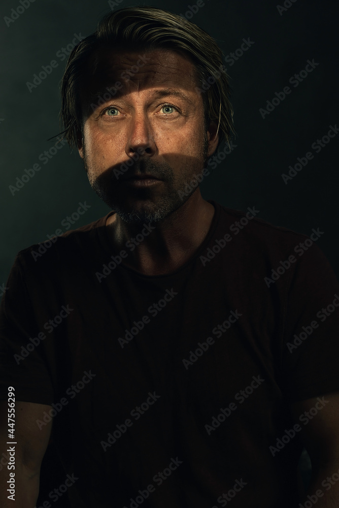 Fototapeta premium Dark mysterious portrait of a blond man with light blue eyes and