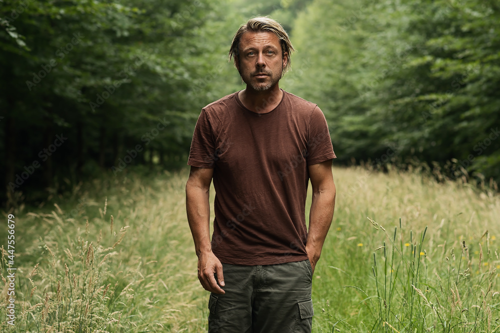 Blonde man with a stubble beard in a brown t-shirt walks on a fo Blonde man with a stubble beard in a brown t-shirt walks on a fo