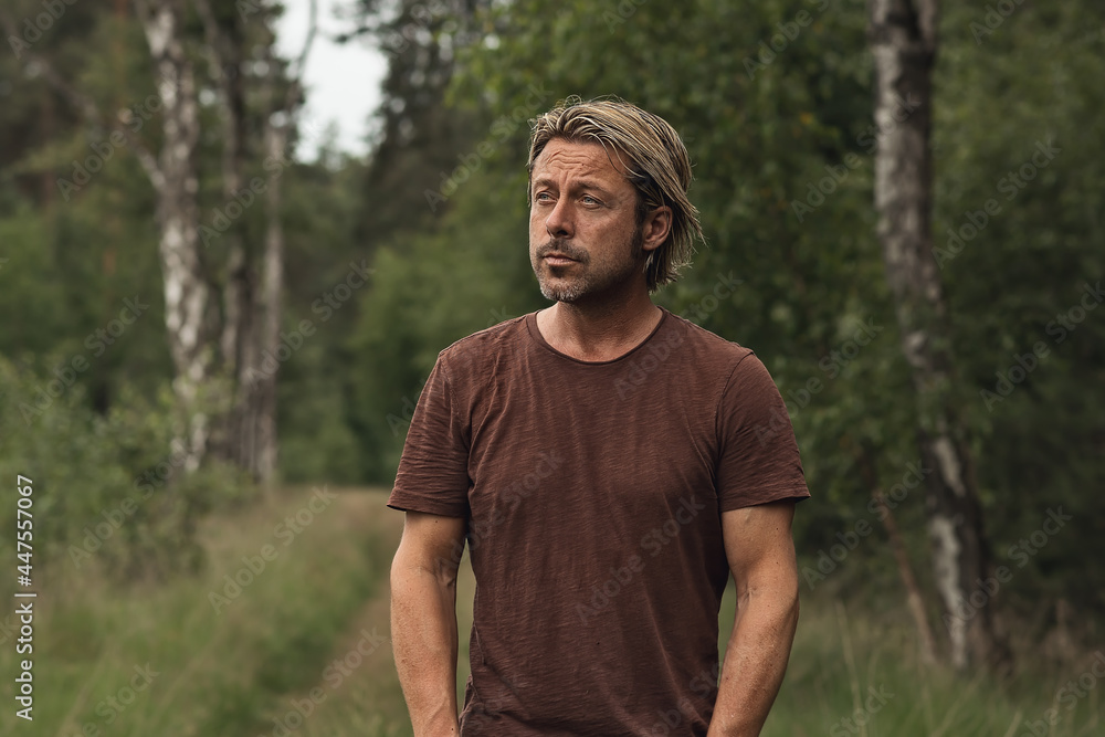 Blonde man with a stubble beard in a brown t-shirt on a forest p Blonde man with a stubble beard in a brown t-shirt on a forest p