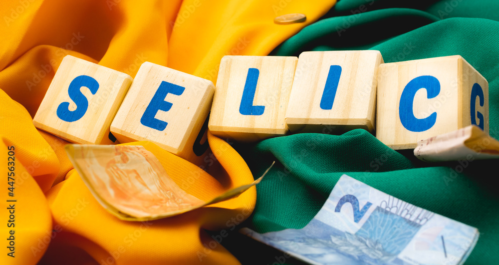 Palavra SELIC escrita em cubos de madeira com algumas cédulas do Real Brasileiro. Fundo em cores amarelo e verde associando ao Brasil.  - obrazy, fototapety, plakaty 