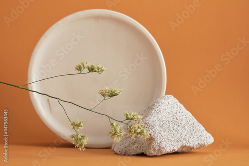 concrete block fragment and round marble podium, blade of grass on brown background