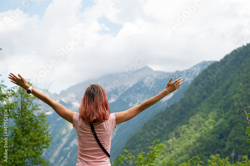 Young woman standing outside in green nature looking at mountains © Gajus