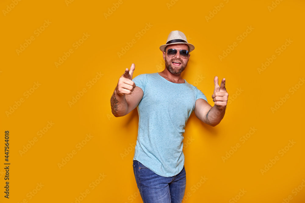 Young handsome man wearing casual t-shirt standing over isolated yellow background pointing with finger to the camera and to you, hand sign, positive and confident gesture