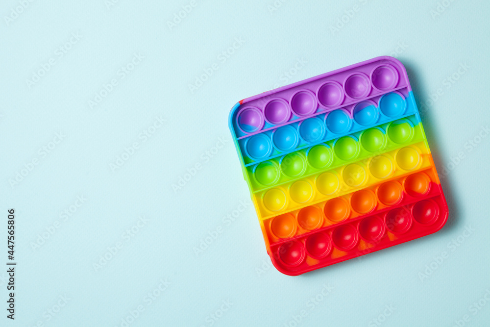 Rainbow silicone sensory antistress pop it toy on light blue background. Top view. Rainbow silicone sensory antistress pop it toy on light blue background. Top view.